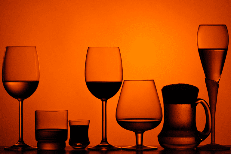 Glasses of alcohol in shadows on a red background