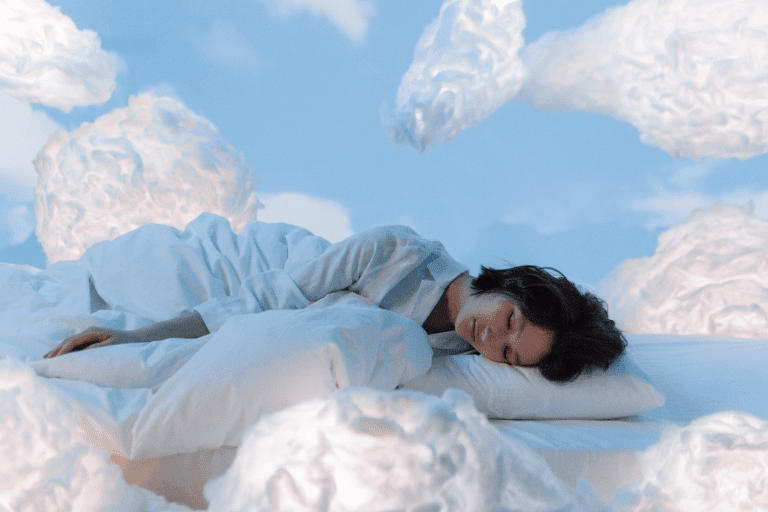 a woman laying on a bed in a cloud filled sky.