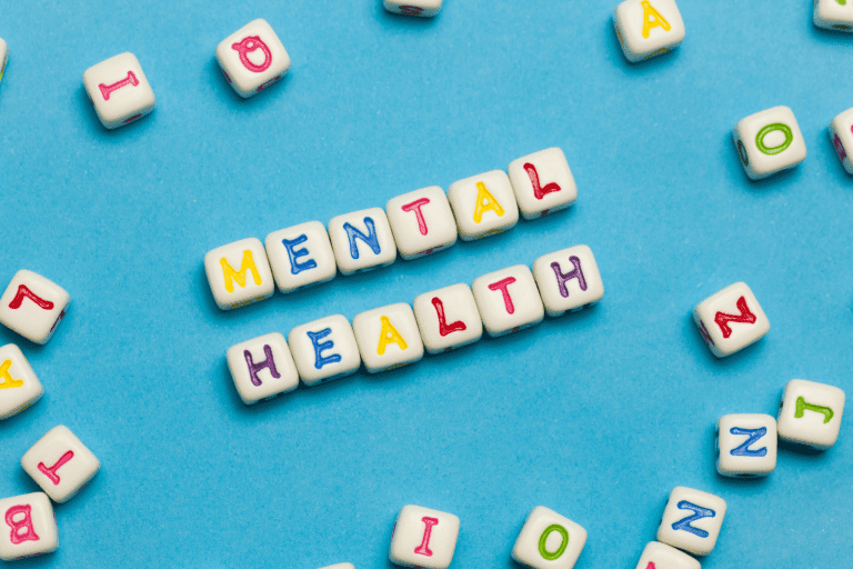 the word mental health spelled with dices on a blue background.