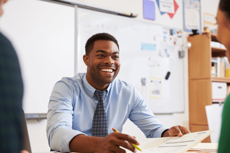 A teacher sitting at his desk smiling