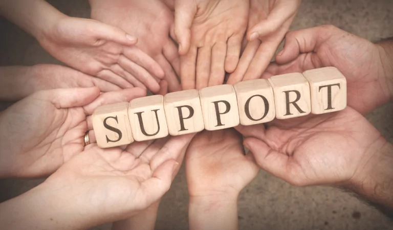 a group of people holding wooden blocks that spell out support.