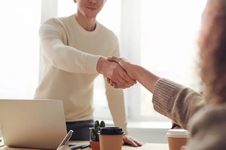 a man and woman shaking hands in an office.