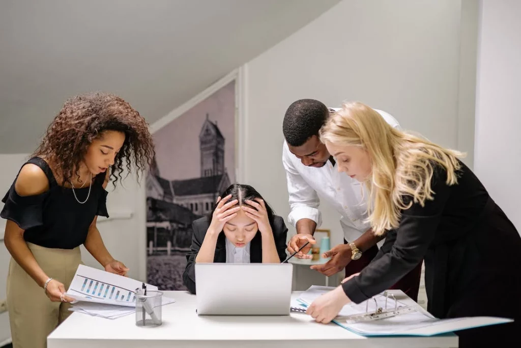 a group of business people looking at a laptop in an office.